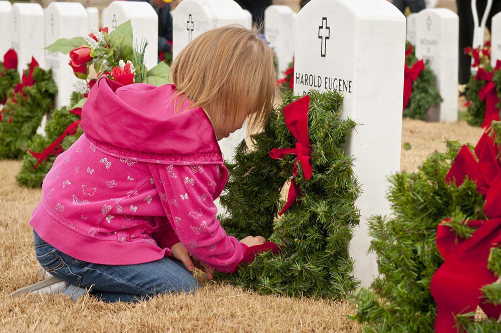 young girl at military cemetery with Christmas wreathes